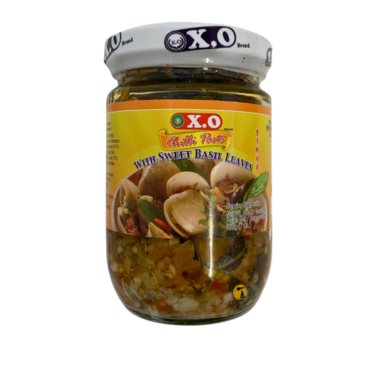 Jar of X.O brand pickles with sweet basil leaves on a white background