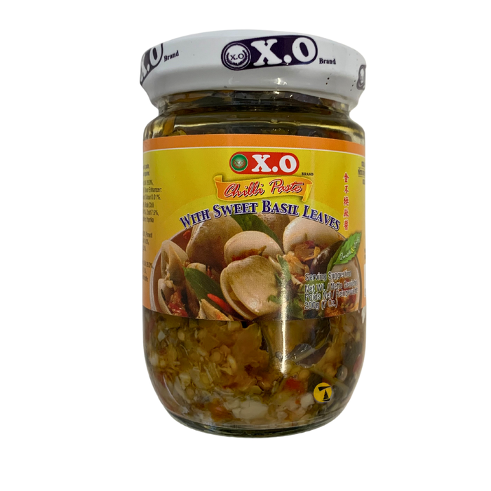 Jar of X.O brand pickles with sweet basil leaves on a white background